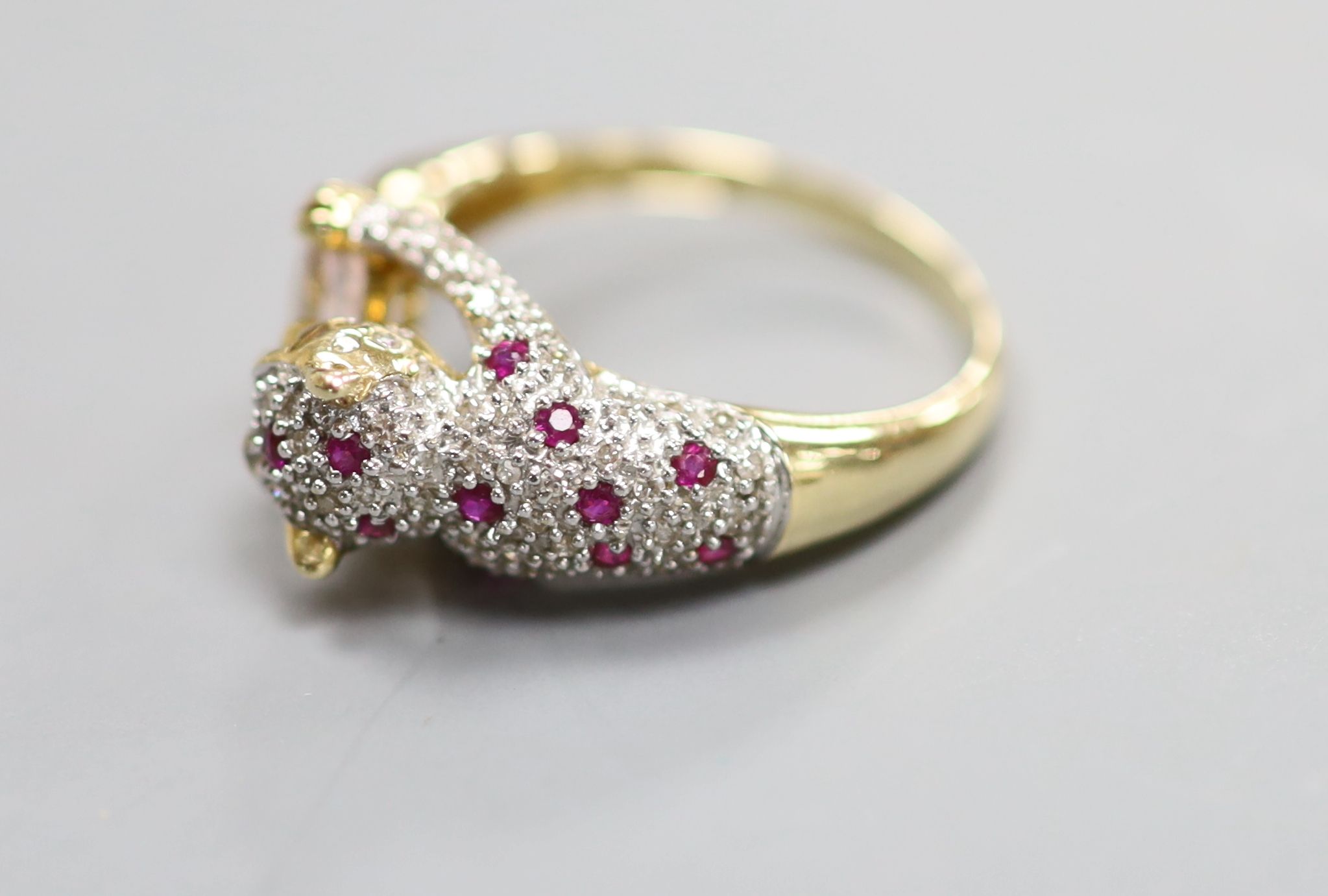 A modern Cartier style 585 yellow metal, pink topaz?, ruby and diamond encrusted leopard ring